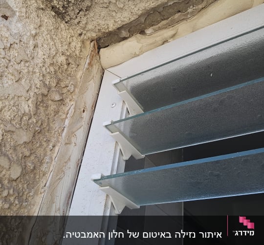 חלון עם תריסים זכוכית וקיר מתקלף